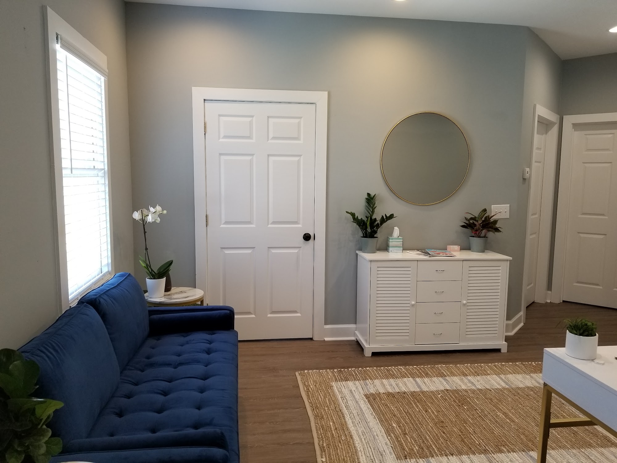 Waiting area with a navy sofa and white dresser